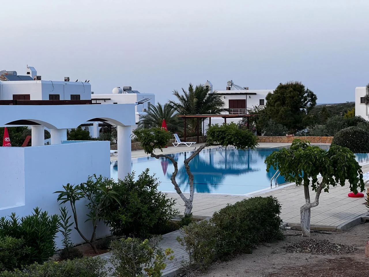 Whitewashed villas around a shared swimming pool at dusk in Northern Cyprus